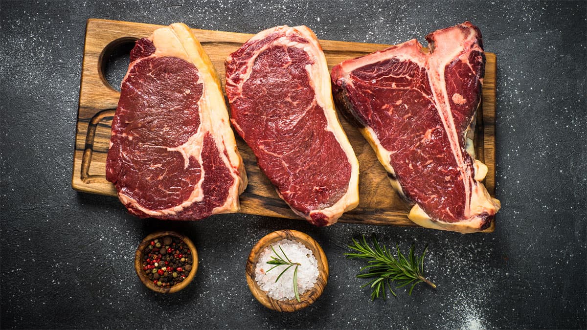 Cutting board with three ISA Foods steaks and small condiment bowls